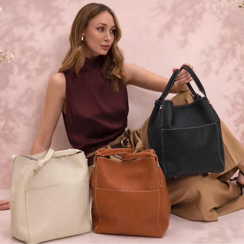 Woman holding a black handbag with three other bags in front of a floral background