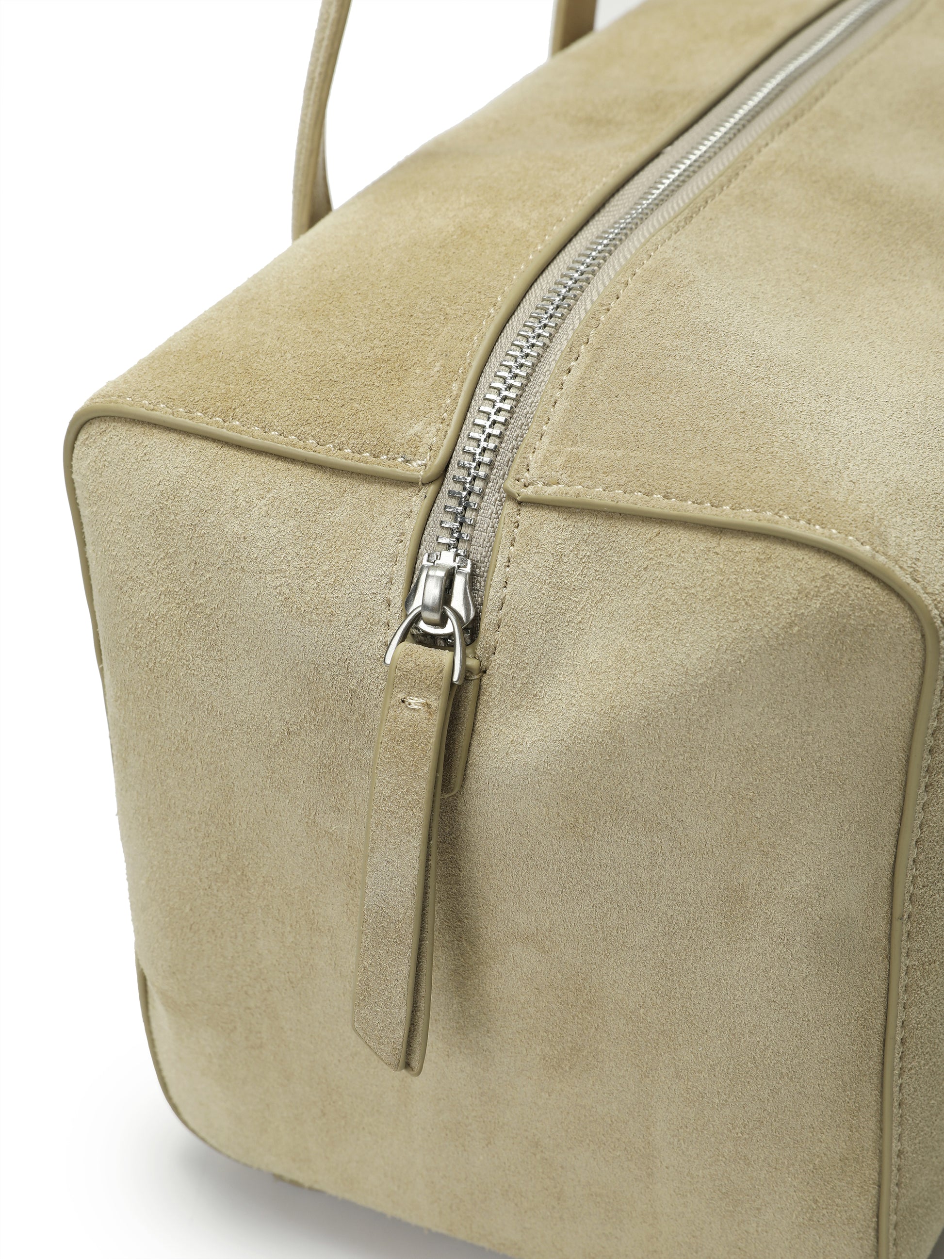Beige suede handbag with silver zipper and structured design, close-up detail