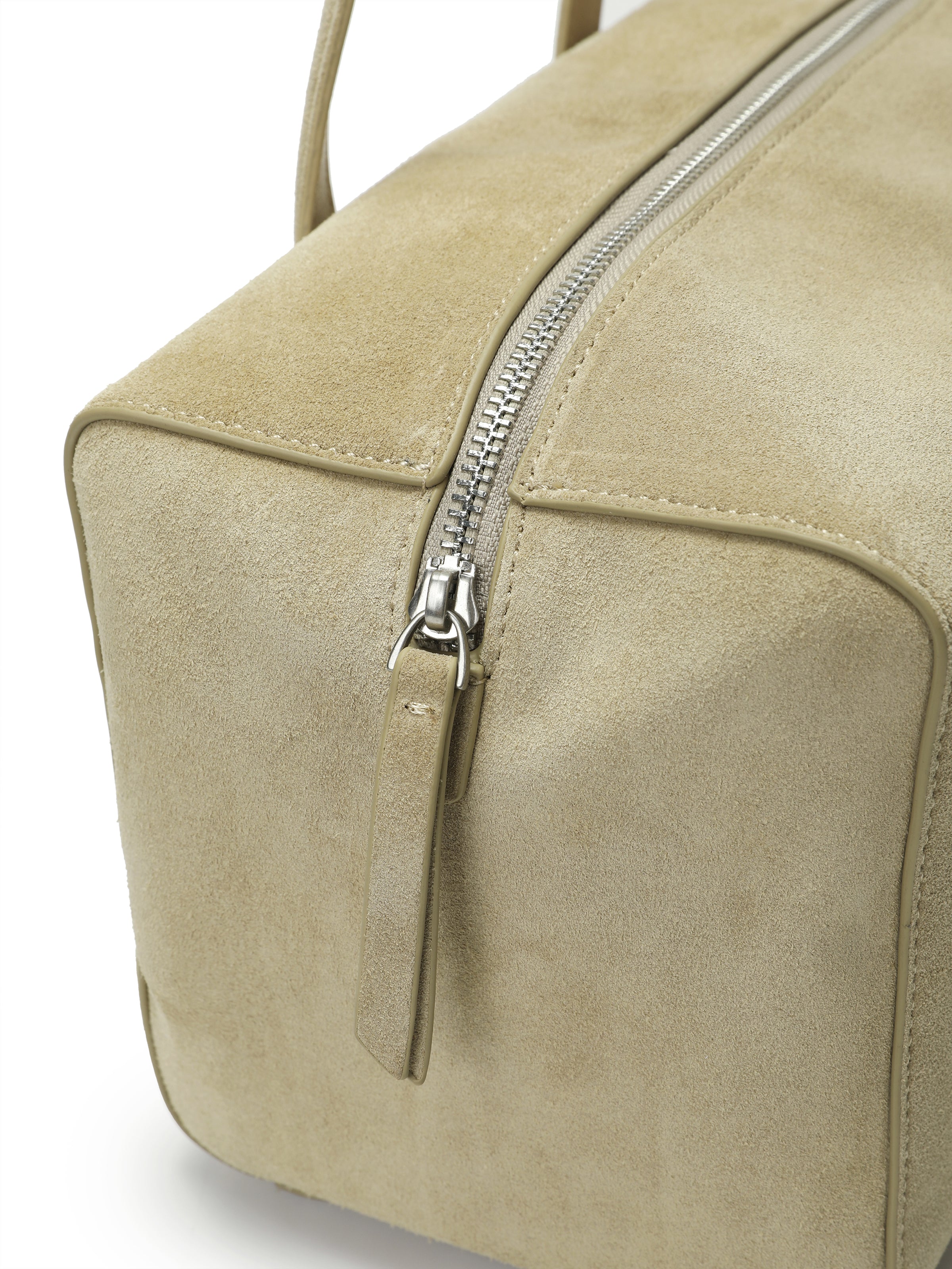 Beige suede handbag with silver zipper and structured design, close-up detail